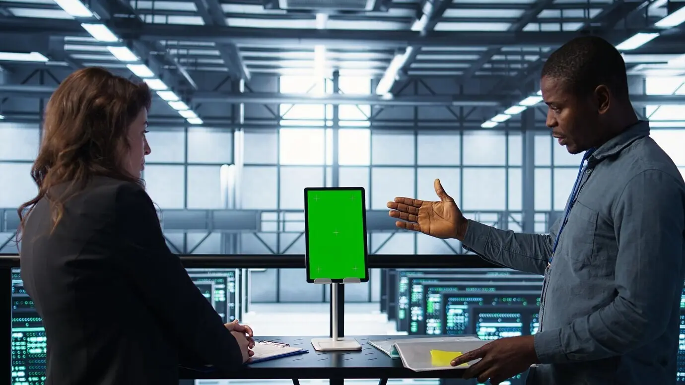 Программисты в дата-центре, используя планшет-макет, следят за аналитикой оборудования.