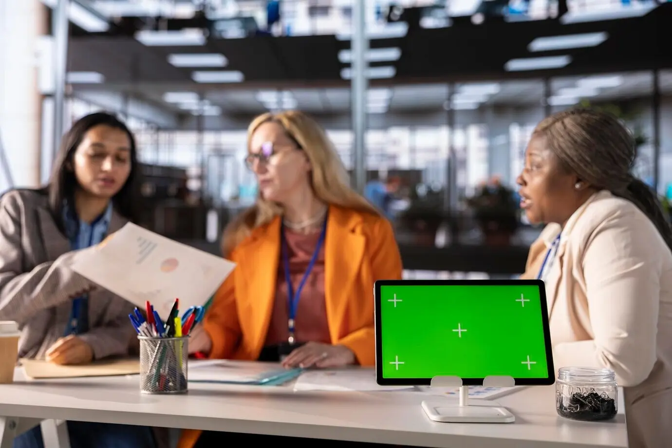 Бизнесвумен разных национальностей работают рядом с изолированным зелёным экраном.