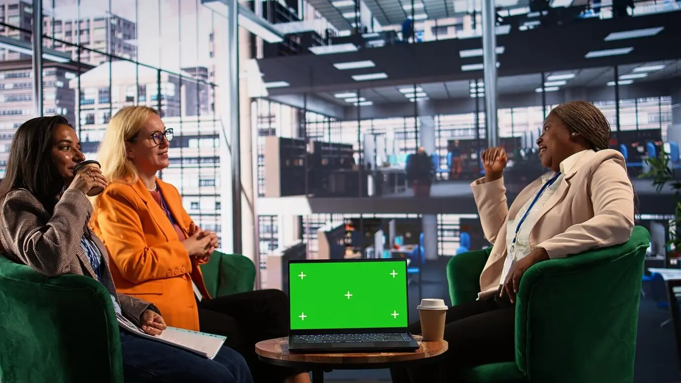 Женщины разной этнической принадлежности обсуждают новые стратегии рядом с зеленым экраном.